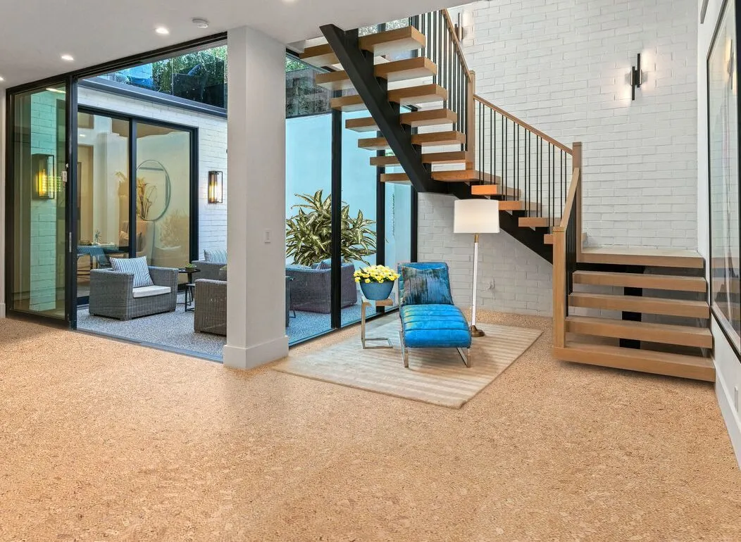 Natural cork flooring beside a timber staircase and a blue armchair.