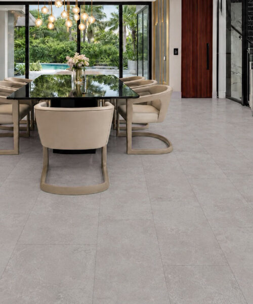 A black dining table and cream chairs contrast with Bright Stone TechSlate flooring’s softly varied gray mineral surface.