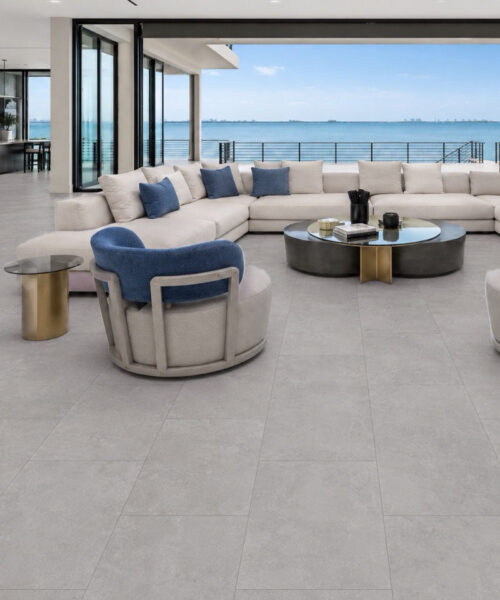 Bright Stone TechSlate flooring unifies an open-plan living room and kitchen with a subtle gray stone-inspired pattern and ocean view.