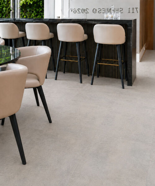 Bris Stone - 7/16" (11mm) - Swiss Design Cork Floating (FBsSt11) Bris Stone floating cork flooring with subtle gray-beige variation spans a home bar beside wooden stairs.