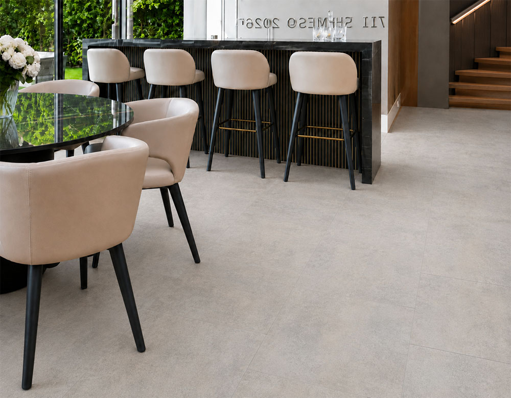 Bris Stone - 7/16" (11mm) - Swiss Design Cork Floating (FBsSt11) Bris Stone floating cork flooring with subtle gray-beige variation spans a home bar beside wooden stairs.