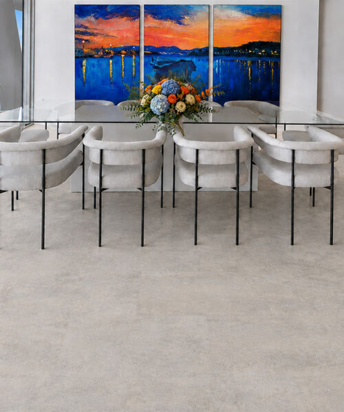 Bris Stone gray-beige stone-look cork flooring fills a waterfront dining room with white upholstered chairs.