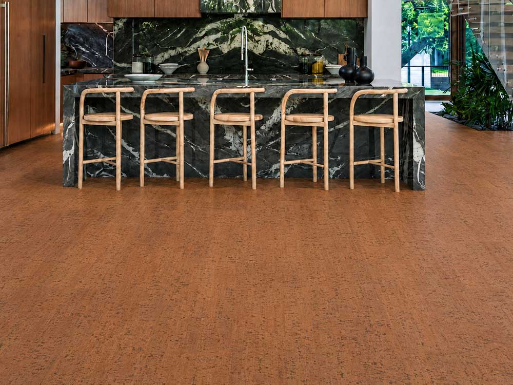Cherry Line - 7/16" (11mm) - Swiss Real Cork Floating (FCHL11) Cherry Line floating cork floor planks frame a dark marble kitchen island with natural wood stools.
