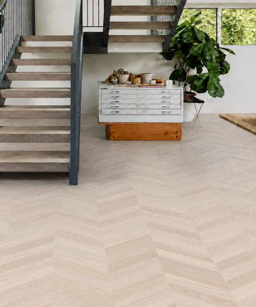 Clara Chevron - 7/16″ (11mm) – Swiss Design Cork Floating (FCla11) Clara Chevron natural cork flooring covers a bright stairway lounge with modern furniture and tropical plants.