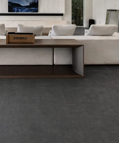 Dark gray Concrete Alloy flooring in a luxury living room with a black marble fireplace and panoramic windows.