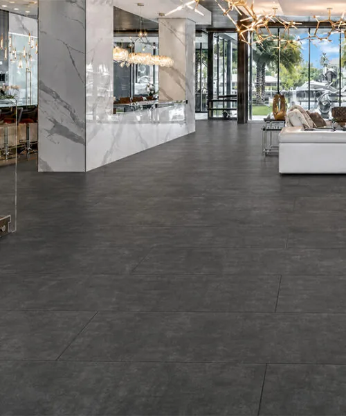 Dark gray Concrete Alloy TechSlate flooring in an open-plan luxury home with marble walls.