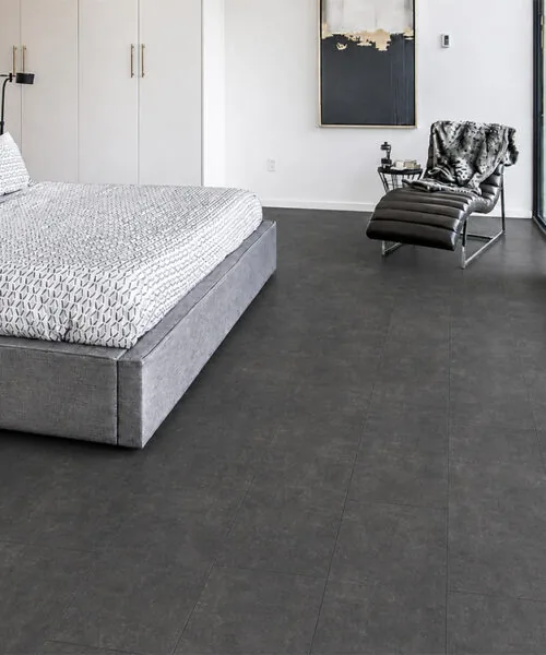 Concrete Alloy gray concrete-look flooring in a modern bedroom with a platform bed and glass doors.