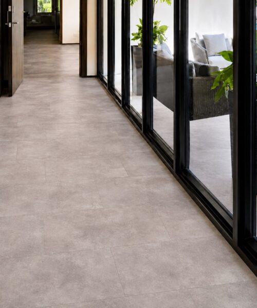 Copperstone Gray - 3/8" (9.5mm) - Forna Natural Composite Flooring with Waterproof Hydrowood Core (NCopG9.5) Copperstone Gray Natural Composite Flooring creates a soft stone-look surface in a bright corridor with floor-to-ceiling windows.