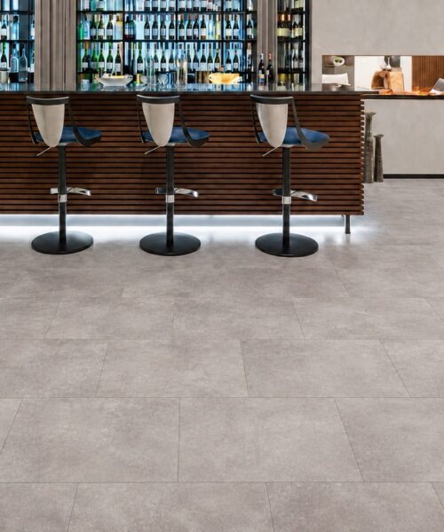 Copperstone Gray natural composite click-lock flooring covers a contemporary entertainment room with wood bar, stools, and linear fireplace.