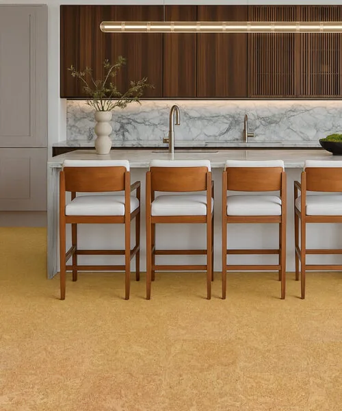 Desert Arable - 25/64" (10mm) - Cork Floating (FDA10) High-end kitchen design showcasing a marble island, wooden cabinetry, and natural Desert Arable cork flooring in a warm yellow-gold tone.
