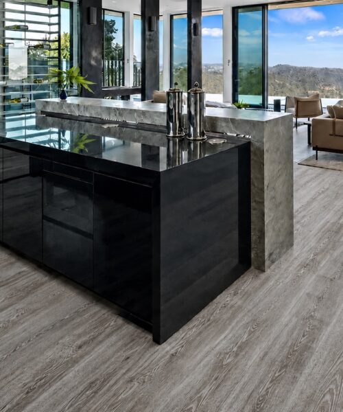 Earthy Pine Natural Composite Flooring displays waterproof floating planks beside a black kitchen island and modern seating.