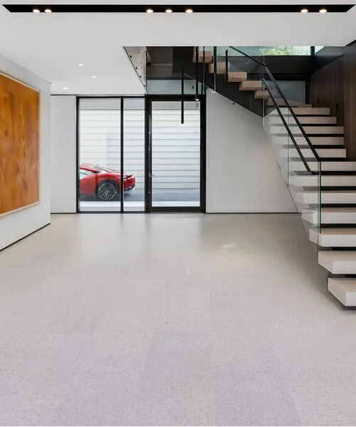 Modern entryway showcasing floating stairs with glass railing and soft neutral Grano cork flooring that adds warmth to a minimalist space.