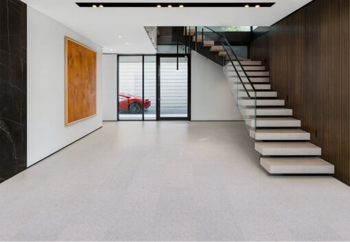 Modern entryway showcasing floating stairs with glass railing and soft neutral Grano cork flooring that adds warmth to a minimalist space.