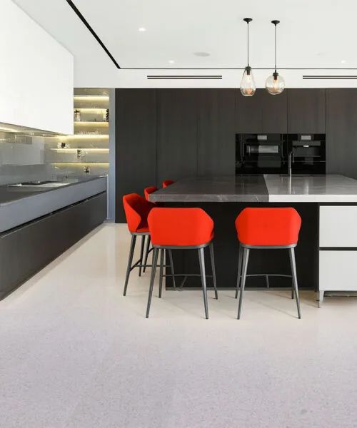 Grano - 25/64" (10mm) - Cork Floating (FGra10) Contemporary kitchen interior featuring natural Grano cork floors, red counter chairs, and matte black cabinetry for a stylish modern contrast.
