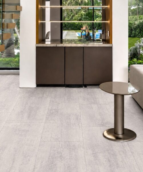 Ivory Concrete Swiss-made Natural Composite Flooring shows square-edge planks in a contemporary living room beside a floating staircase.