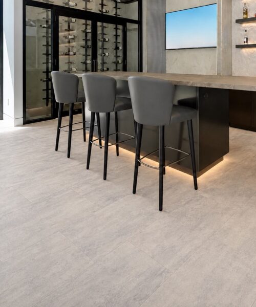 Ivory Concrete - 3/8" (9.5mm) - Forna Natural Composite Flooring with Waterproof Hydrowood Core (NICon9.5) Ivory Concrete waterproof Natural Composite Flooring features subtle gray variation beneath a contemporary bar and wine storage.