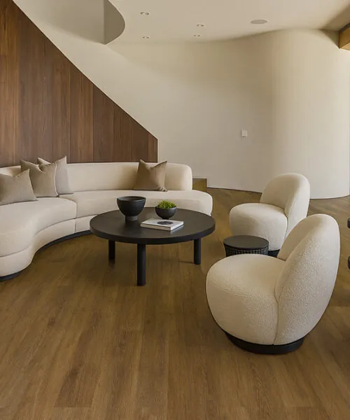 Latte - 7/16" (11mm) - Swiss Design Cork Floating (FLat11) atte Swiss cork flooring in a cozy contemporary lounge with curved sofa and wood accent wall.”
