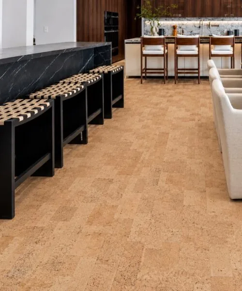 Leather - 1/2" (12mm) - Cork Floating (FLe12) Luxury kitchen featuring Leather Natural cork floating flooring, a dramatic black marble island, and warm wood cabinetry with bar stools.