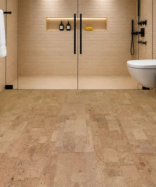 Spa-inspired bathroom featuring Leather Natural 6mm glue-down cork tile flooring, a walk-in glass shower, matte black fixtures, and a warm, comfortable natural cork floor sealed for bathroom use.