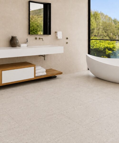 Matera Blend -19/64" (7.5mm) - Swiss Techslate (MMatBd7.5) Matera Blend waterproof floating flooring in light limestone shows mineral variation across rectangular planks beside a freestanding bathroom tub.
