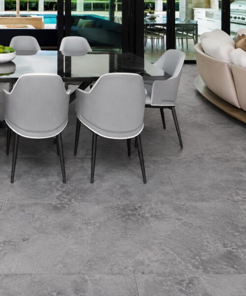 Midnight Slate TechSlate flooring displays a gray mineral pattern beneath a modern dining table and living area beside pool-facing glass doors.