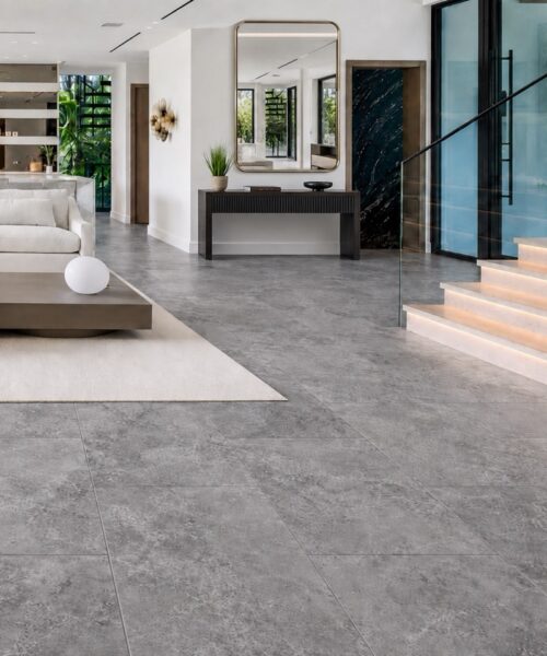 Midnight Slate TechSlate flooring forms a gray mottled surface across an open-plan living area with a kitchen, dining space, and illuminated staircase.