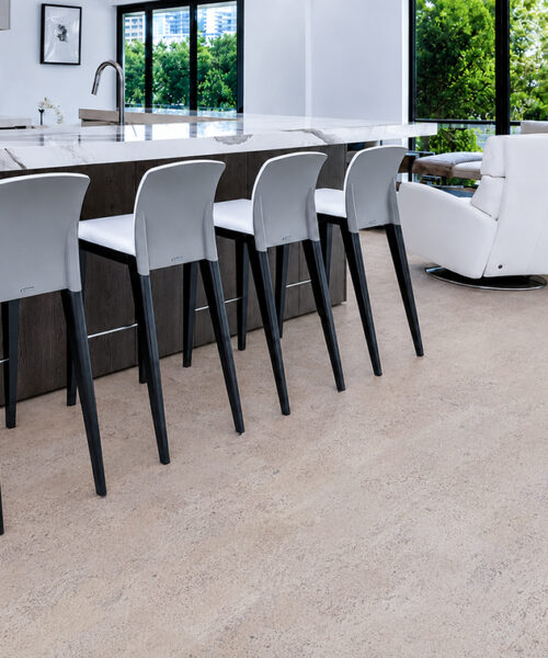 Mystic Vanilla floating cork flooring complements an open kitchen with marble counters, bar chairs, and lounge seating.
