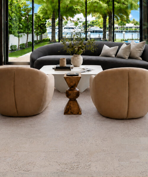 Mystic Vanilla natural cork flooring surrounds curved lounge furniture in a waterfront living room overlooking a pool.