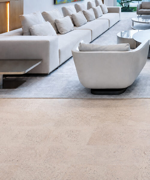 Light beige Mystic Vanilla floating cork flooring borders a gray rug beneath white modern living room seating.