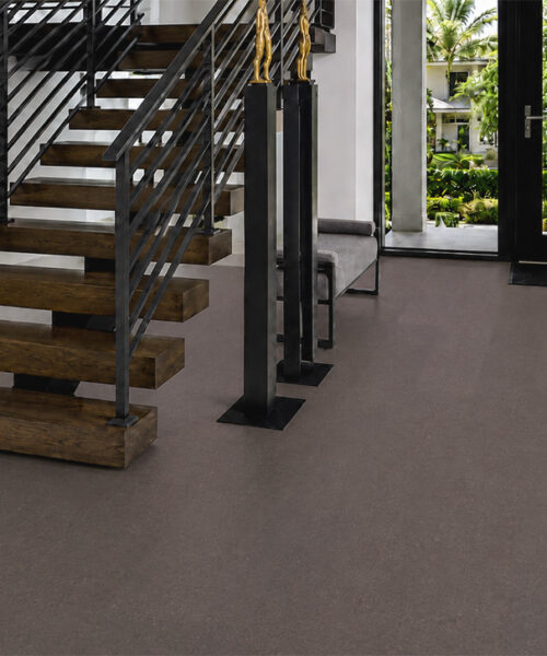 Night Swiss cork floor planks continue through a modern foyer with wooden stairs and glass doors.