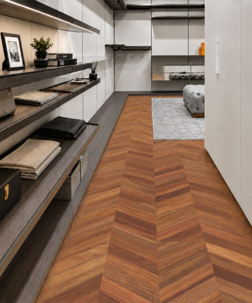 Noble Chevron walnut cork floor planks lead through a modern dressing room with illuminated open shelving.