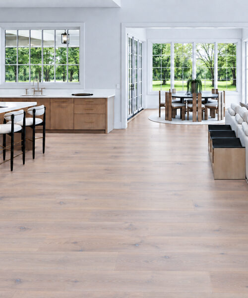 Light gray Nordic Oak wood-look Natural Composite Flooring flows across a bright kitchen, dining nook, and living area.