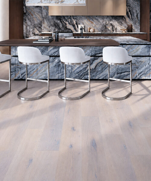 Pale gray Nordic Oak wood-look Natural Composite Flooring grounds a dramatic marble island and four white counter stools.