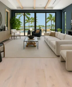 Contemporary living room featuring Nordic Oak Swiss Real Linoleum Flooring in soft beige-oak tones, complemented by modern neutral furniture and a bright coastal view.