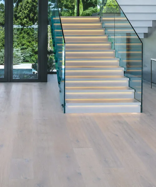 Nordic Oak - 3/8" (9.5mm) - Forna Natural Composite Flooring with Waterproof Hydrowood Core (NNorO9.5) Light Scandinavian oak flooring installed in a spacious home foyer beside a contemporary staircase