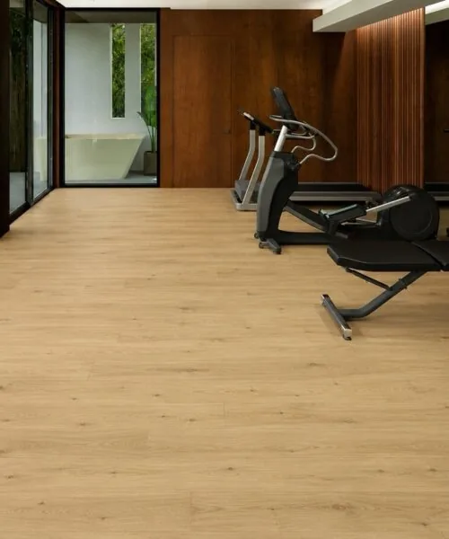 Durable Long Beach Swiss Design cork floating flooring installed in a modern home fitness room with premium exercise equipment and warm natural oak appearance.