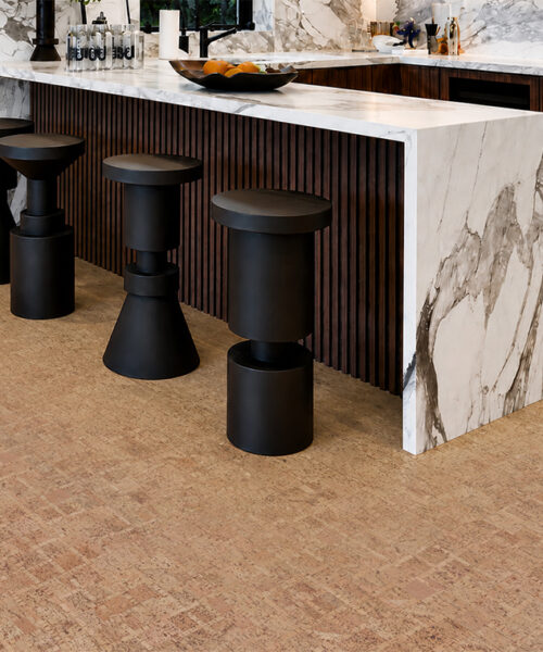 Light brown ParCork natural cork flooring grounds a modern kitchen with marble counters and black stools.