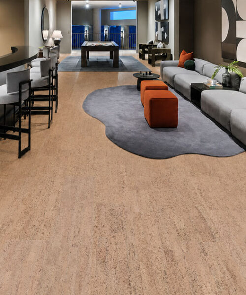 Rhythm – 7/16″ (11mm) – Swiss Real Cork Floating (FRhy11) Rhythm quiet cork flooring runs between a curved home bar and a long gray sectional sofa.