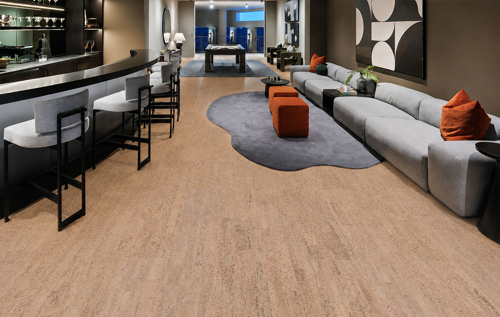 Rhythm – 7/16″ (11mm) – Swiss Real Cork Floating (FRhy11) Rhythm quiet cork flooring runs between a curved home bar and a long gray sectional sofa.