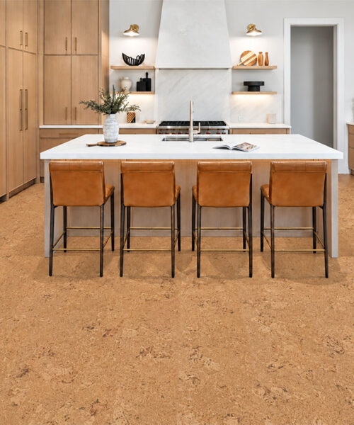 Salami gold-oak cork floor planks ground a bright kitchen with wood cabinets and four counter stools.