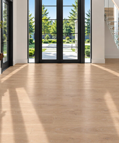 Sandstorm - 7/16" (11mm) - Swiss Design Cork Floating (FSan11) Warm sand-colored cork flooring with subtle hardwood grain in a bright entryway featuring glass doors, floating stairs, and a live-edge console.