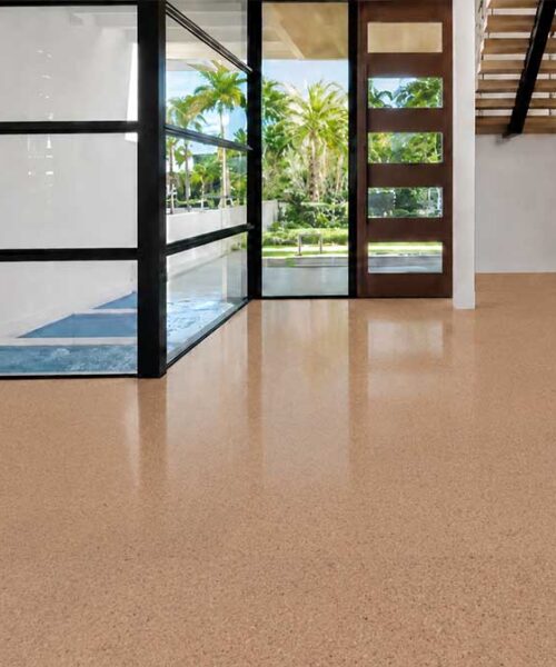 Seaside Swiss cork flooring with subtle speckling extends through a bright entryway beside an open staircase.