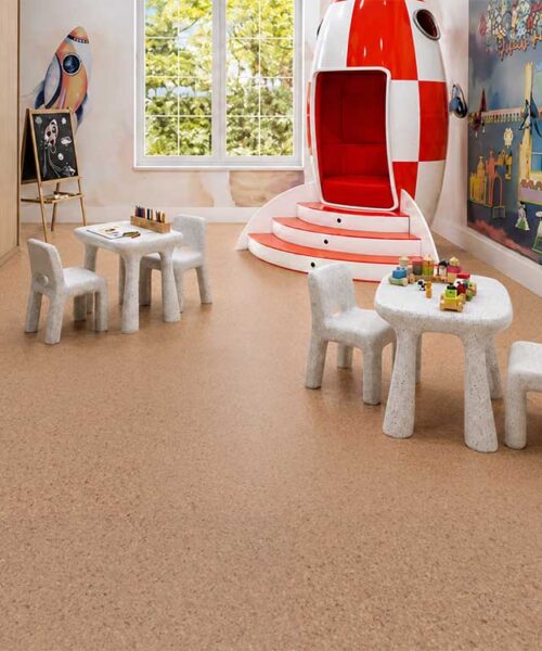 Warm Seaside floating cork flooring covers a children’s playroom furnished with tables and rocket decor.