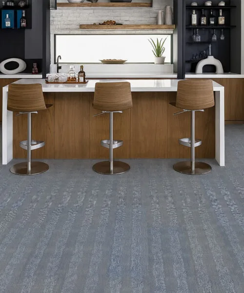 Stylish kitchen bar with Serpent Luxe Swiss leather flooring, elegant gray-blue tones creating a durable foundation for wood cabinetry.