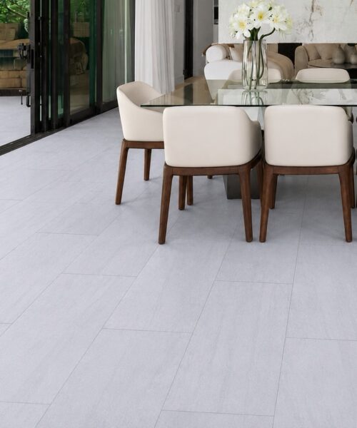 Snowstone light gray mineral-based flooring forms a staggered plank layout in a modern entryway with black-framed glass doors.