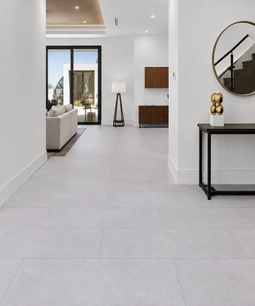 Snowstone light gray click-lock flooring extends through a bright hallway beside a console table and contemporary staircase.