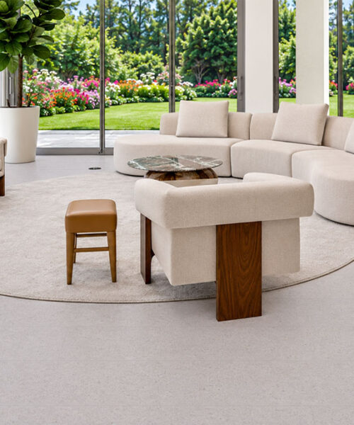 Sustainazzo - 25/64" (10mm) - Cork Floating (FSus10) Sustainazzo terrazzo-inspired cork flooring surrounds curved neutral seating in a sunlit living room overlooking gardens.