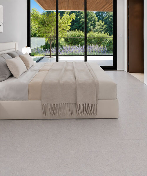 Sustainazzo - 25/64" (10mm) - Cork Floating (FSus10) Sustainazzo white terrazzo-look cork flooring complements a minimalist bedroom with soft bedding and patio views.