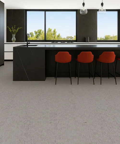 Contemporary kitchen with black island and red bar stools on light gray cork flooring, sleek modern style