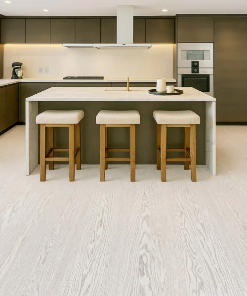 Contemporary kitchen with Swiss Snow Cap real wood floating flooring, brown cabinets, marble island, and three wooden bar stools.